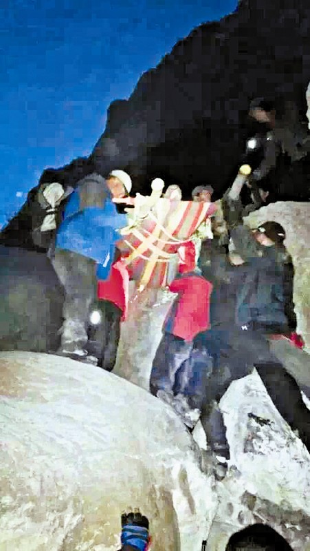 救援隊(duì)員用自制的簡易擔(dān)架抬傷者。